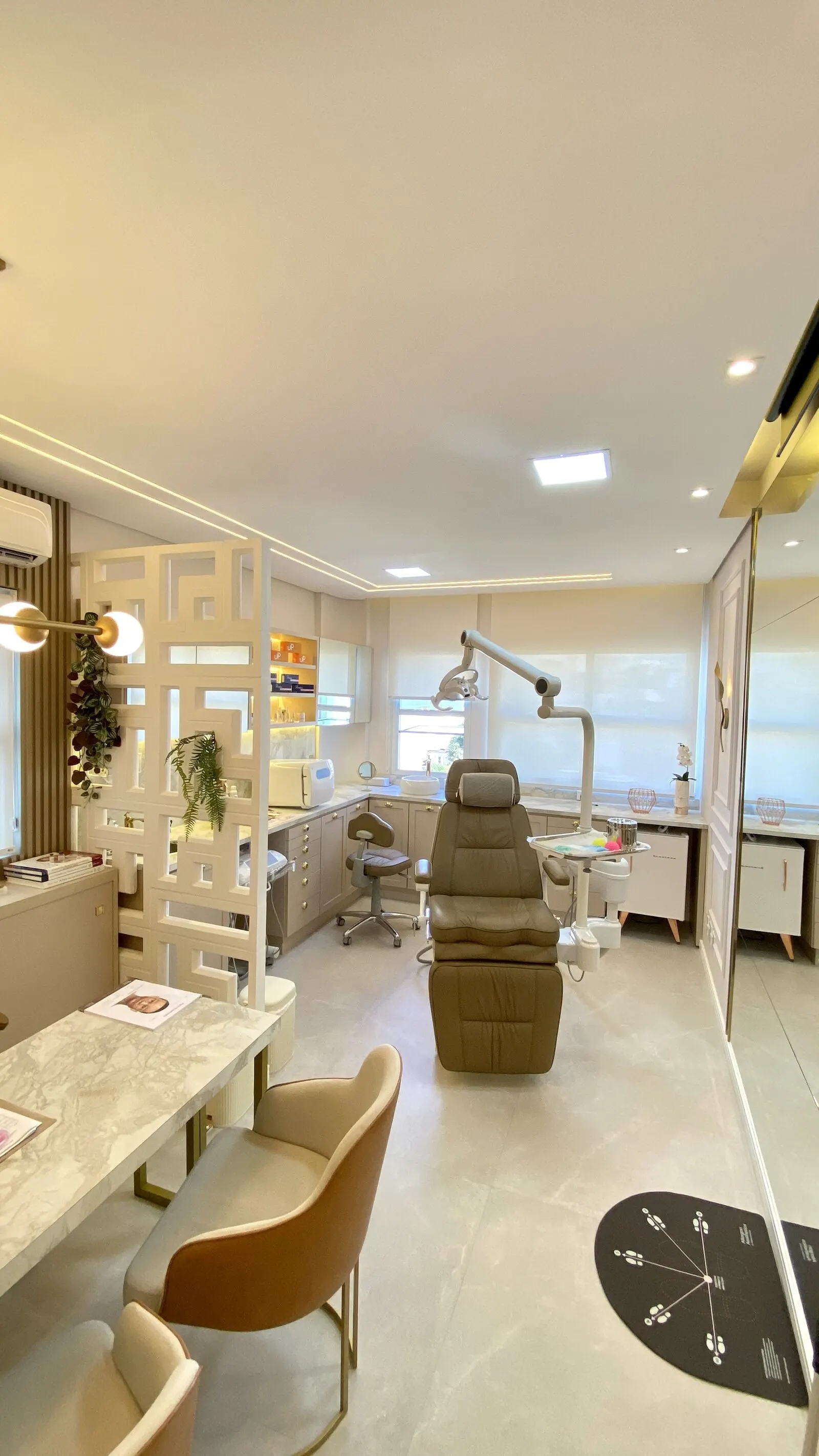 Sala de atendimento da clínica, com poltrona reclinável, bancada de mármore e iluminação embutida